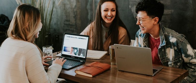 three people sitting in front of table laughing together
